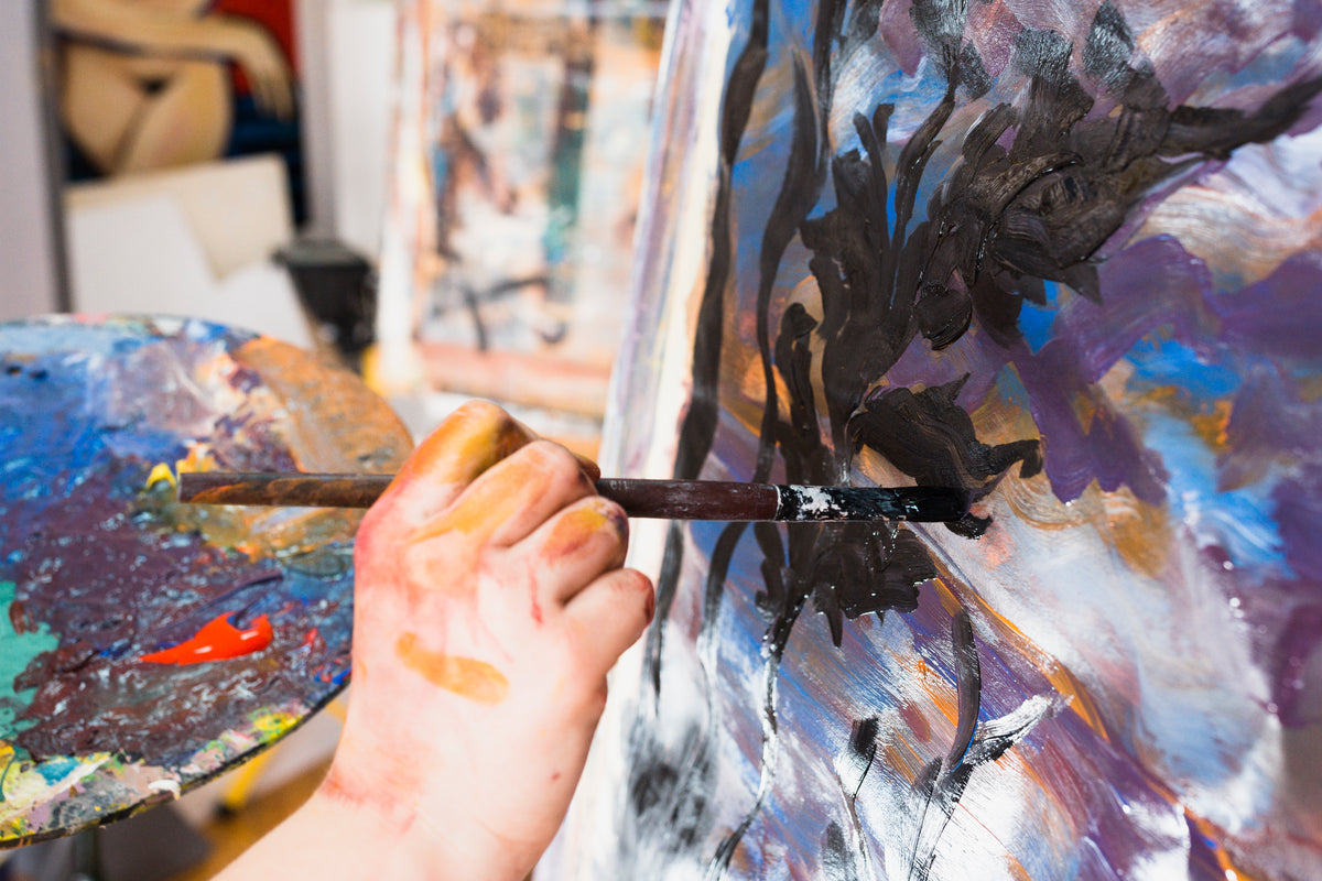 Main d’artiste peignant une toile au pinceau